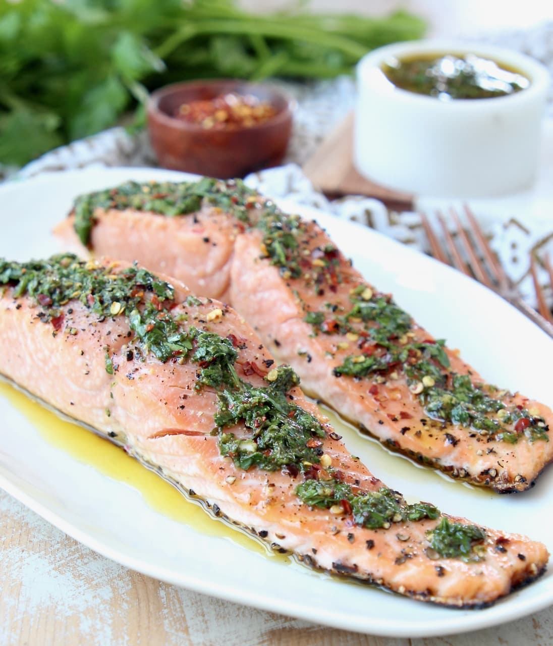 Slices of salmon on plate topped with chimichurri sauce