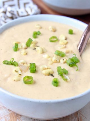 Corn soup in bowl topped with corn kernels and diced green onions