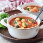 Tomato basil gnocchi soup in white bowls on wood tray