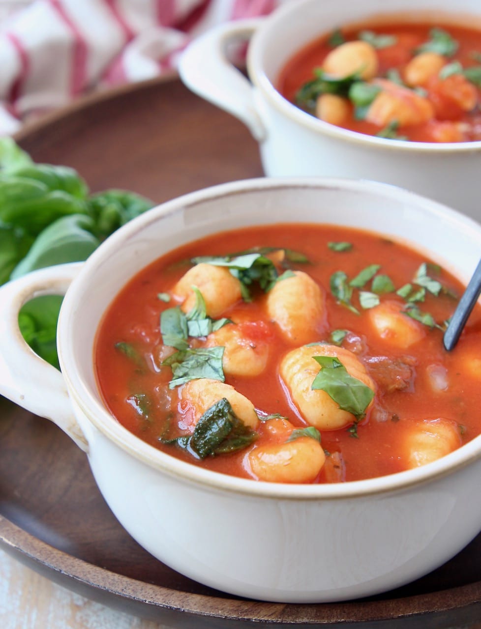 Tomato basil gnocchi soup in white bowls with spoons