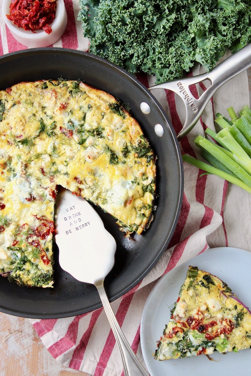 Frittata in skillet, with slice cup out on plate to the side