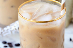 Long island iced coffee in glass with gold and white striped straw