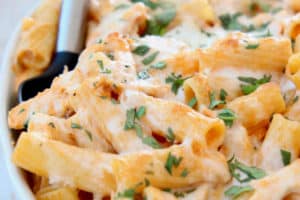 Cheesy pasta in casserole dish with serving spoon