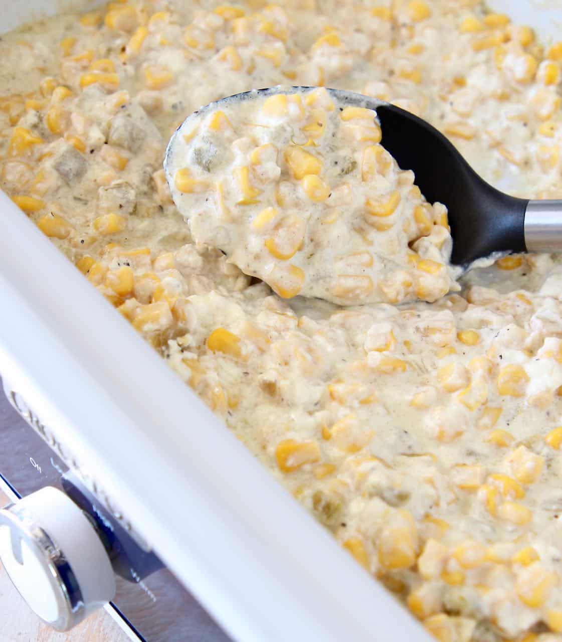 Creamed corn in slow cooker with serving spoon