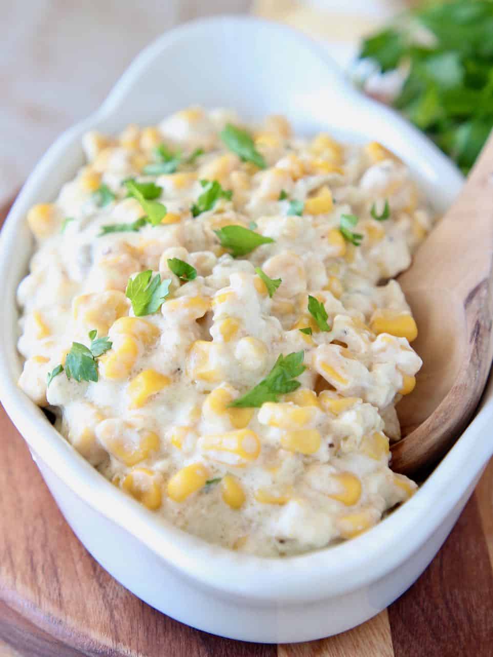 Creamed corn in serving dish with wooden spoon