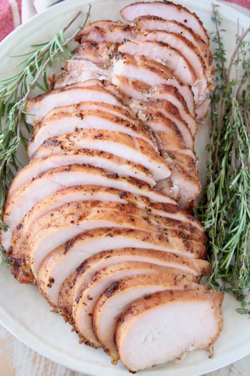 Sliced smoked turkey breast on plate with fresh herbs