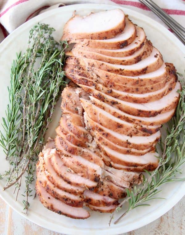 Slices of smoked turkey breast meat on plate with fresh herbs