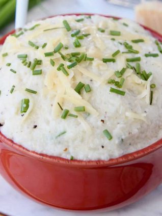 Cheesy mashed cauliflower in dark orange bowl