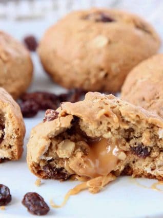 Oatmeal raisin cookie cut in half with caramel coming out of the center