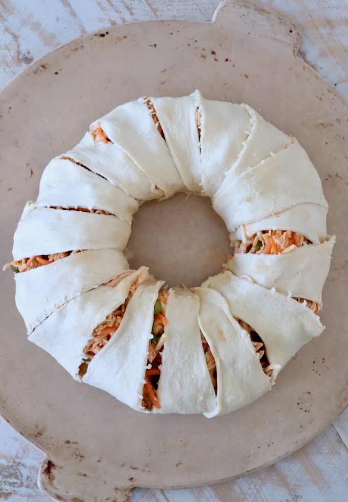 uncooked buffalo chicken pastry ring on round stone baking dish