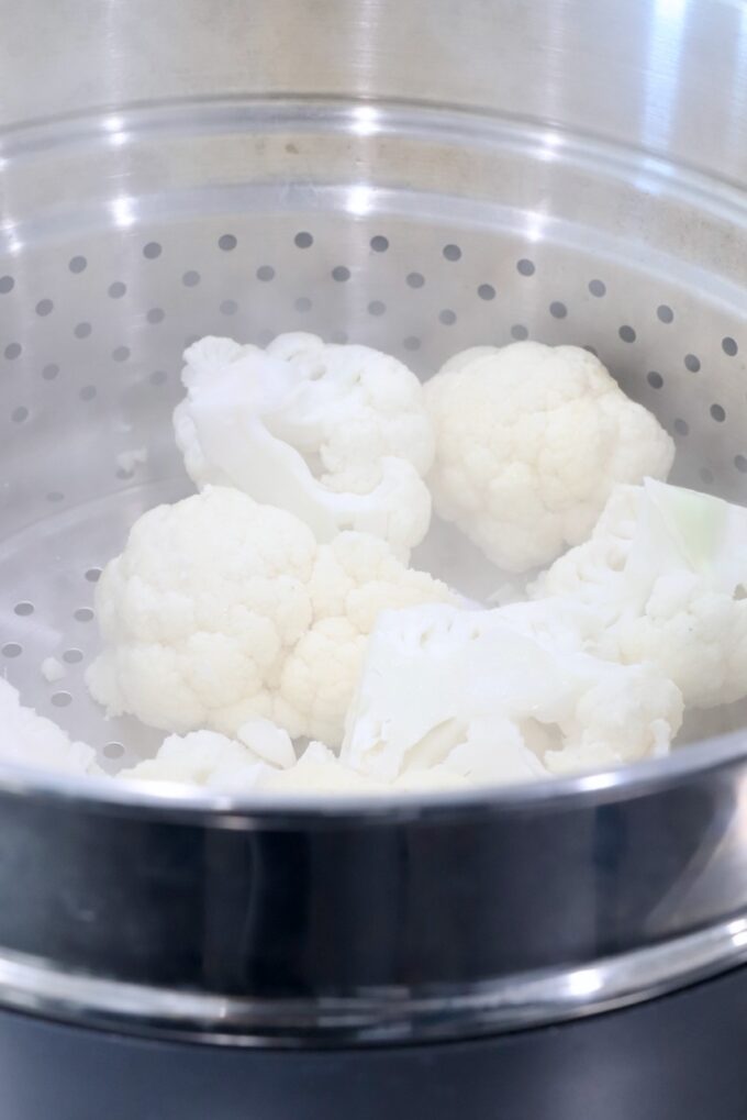 cauliflower in a steamer basket in a pot