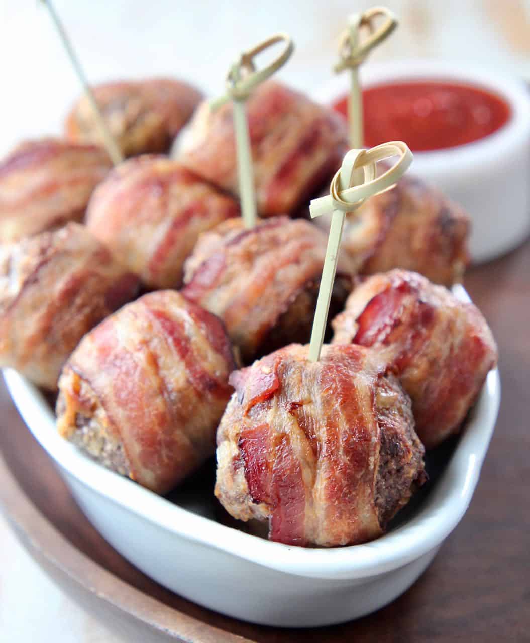 Bacon wrapped meatballs in bowl with wood skewers