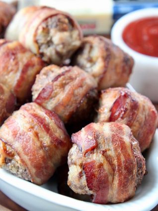 Bacon wrapped meatballs in white dish with bbq sauce on the side