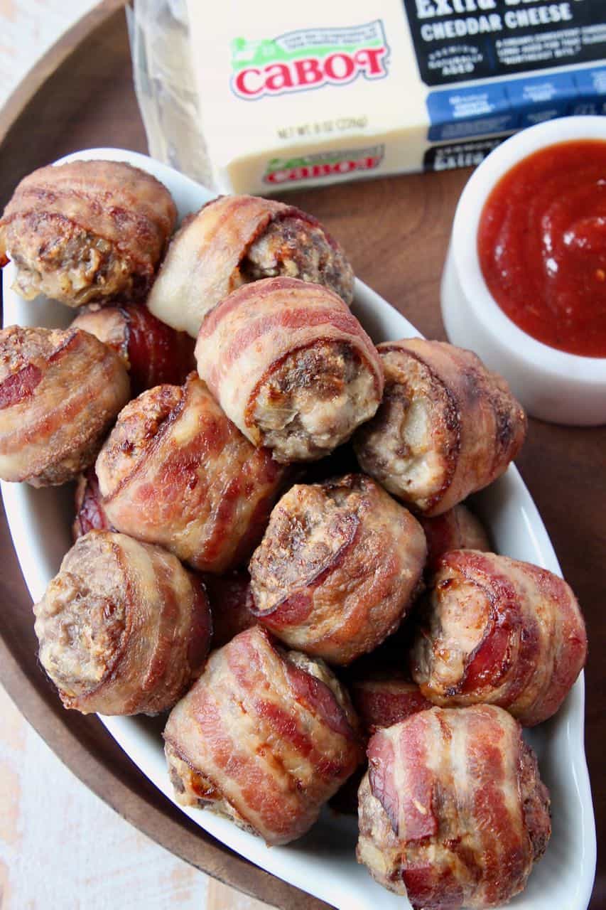 Bacon wrapped meatballs in white serving dish on wood serving tray