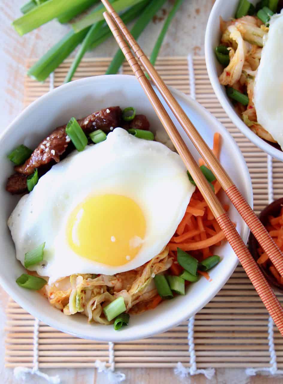 Korean BBQ Cauliflower Rice Bowl topped with a fried egg with chopsticks and green onions