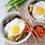 Cauliflower rice bowls topped with fried eggs and shredded carrots