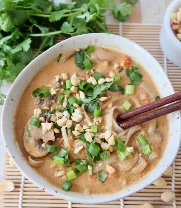 Overhead image of a bowl of Thai noodle soup topped with diced green onions and fresh cilantro