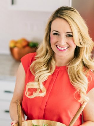 blonde woman in kitchen holding a salad bowl