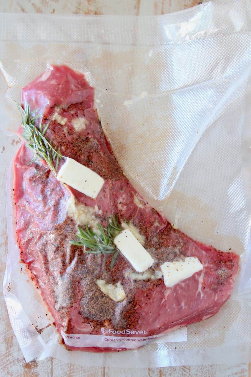 Tri tip steak vacuum sealed in bag with butter and fresh herbs