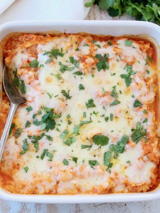 Cheesy buffalo chicken cauliflower casserole with spoon, topped with cilantro