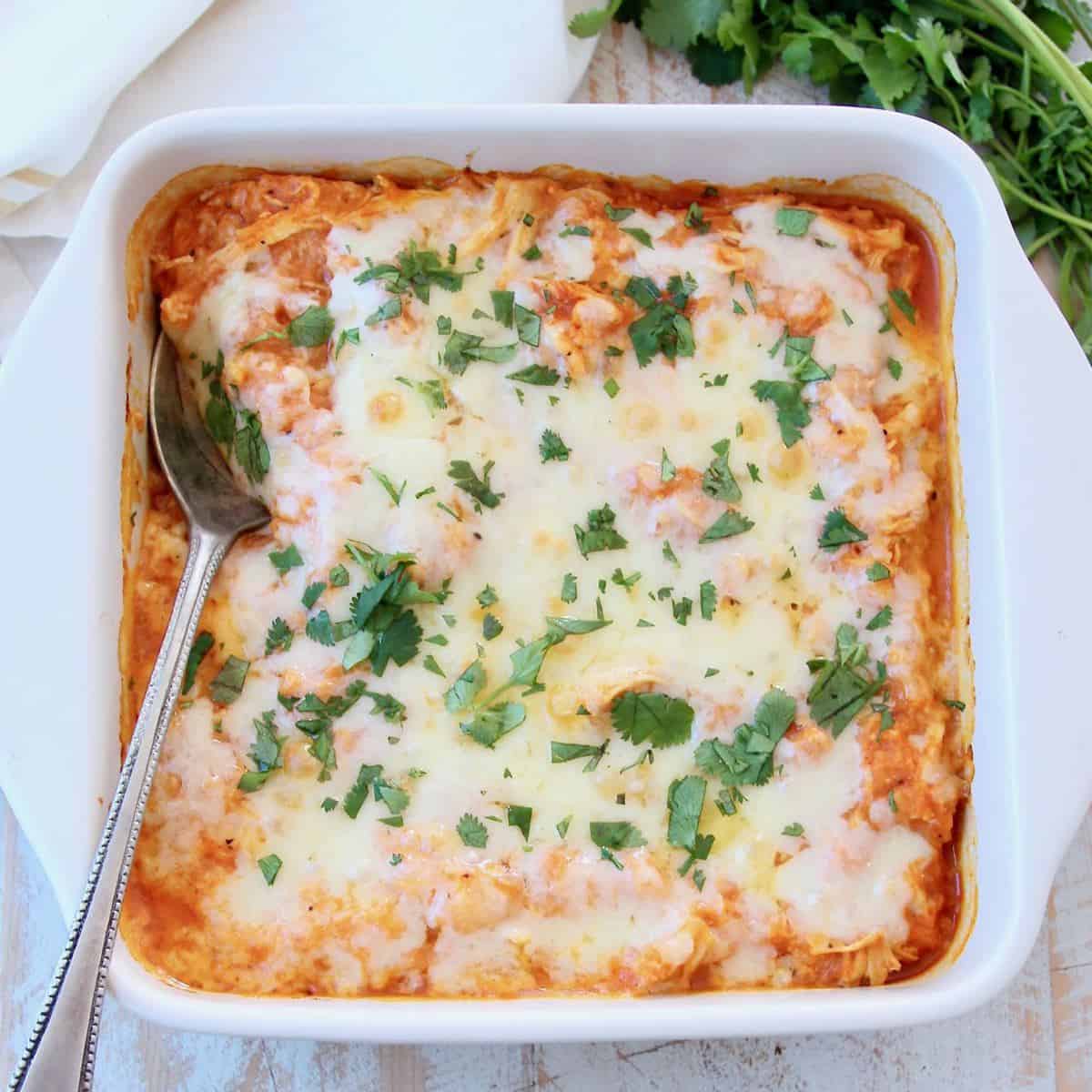 Cheesy buffalo chicken cauliflower casserole with spoon, topped with cilantro