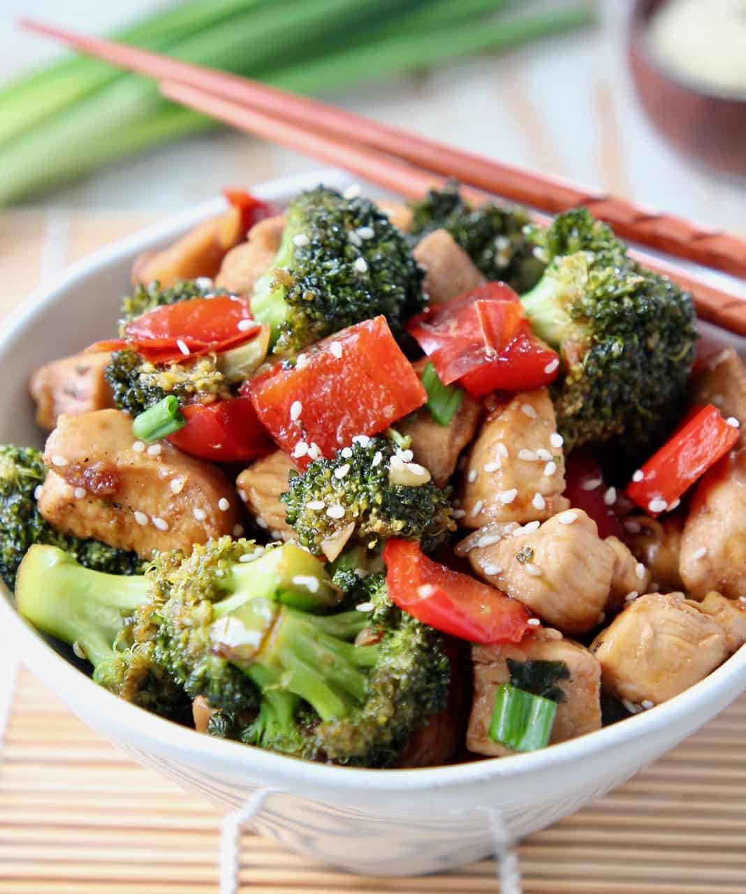 Stir fry teriyaki chicken and broccoli in white bowl with chopsticks on the side