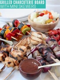Grilled skewers on charcuterie platter with bowls of sauce