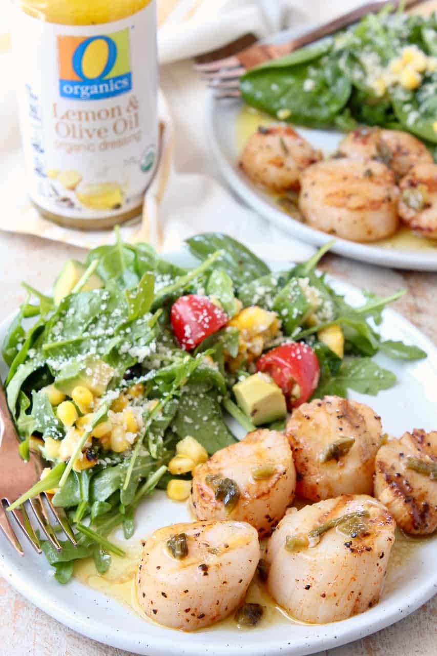 Grilled scallops on plate with arugula salad