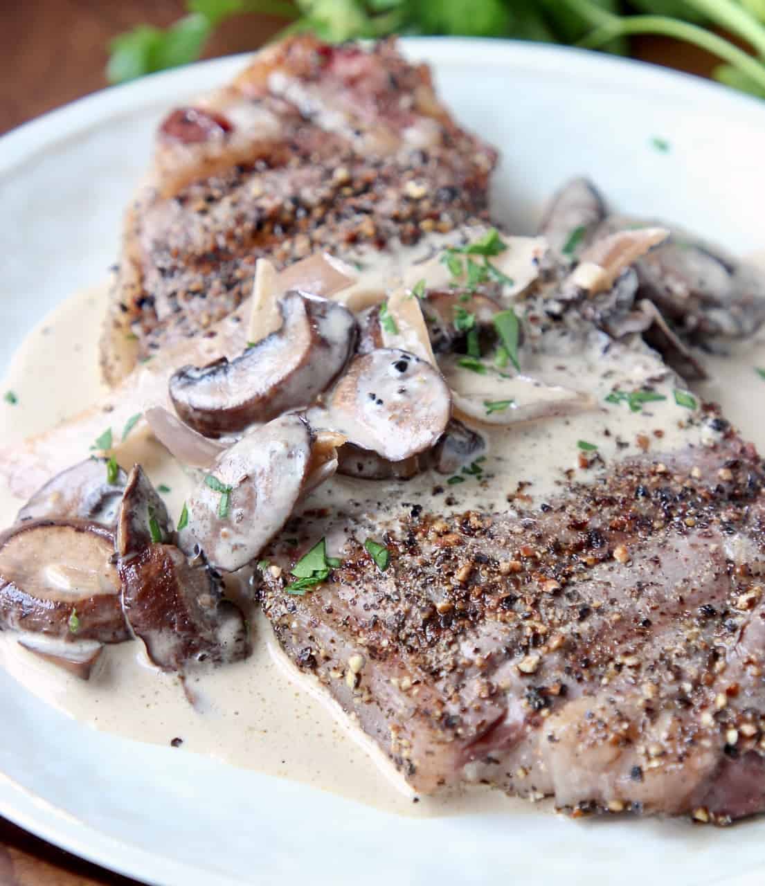 Peppercorn steak on plate, covered with mushroom sauce