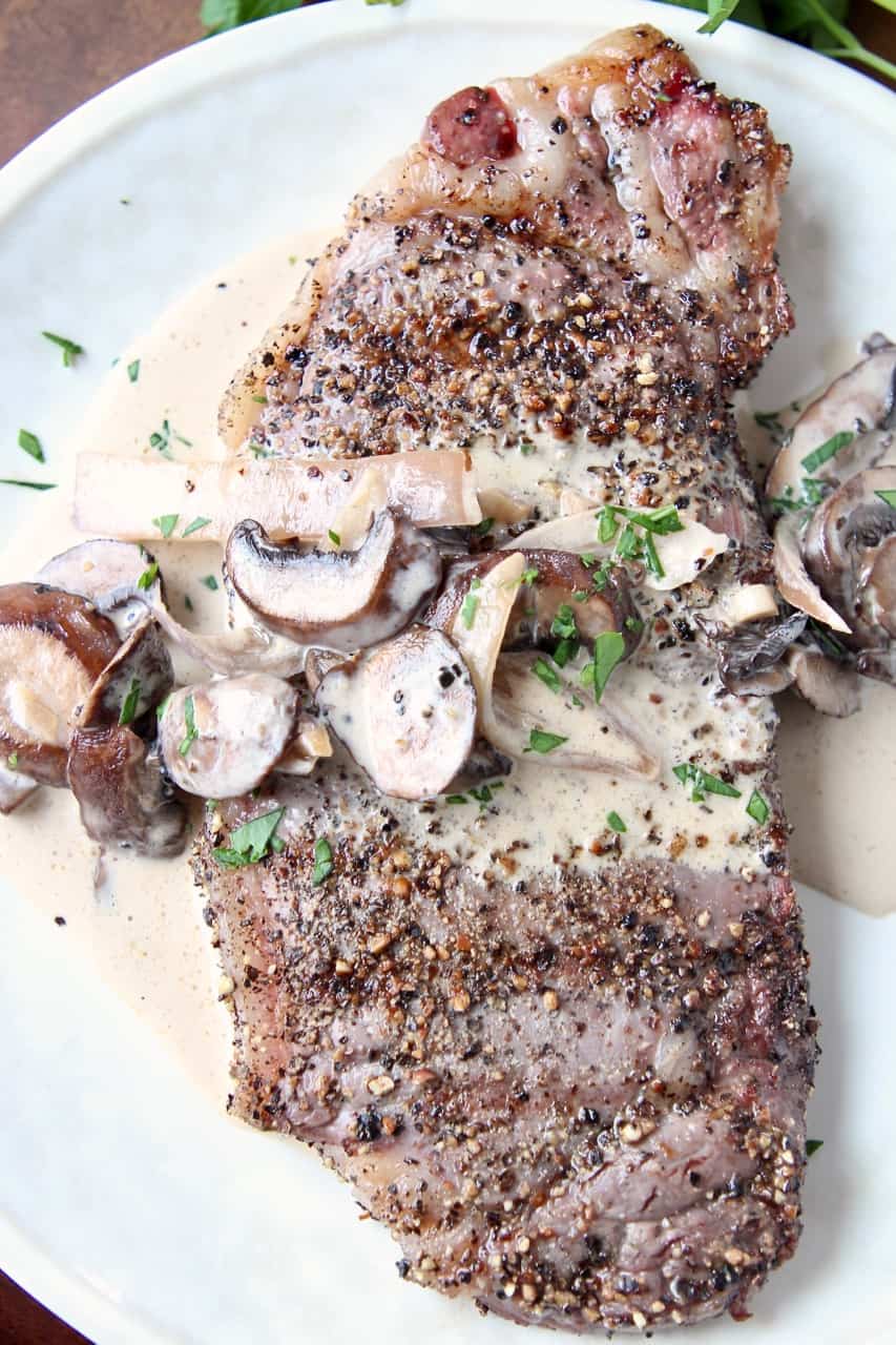 Overhead image of peppercorn steak on plate covered with mushroom sauce