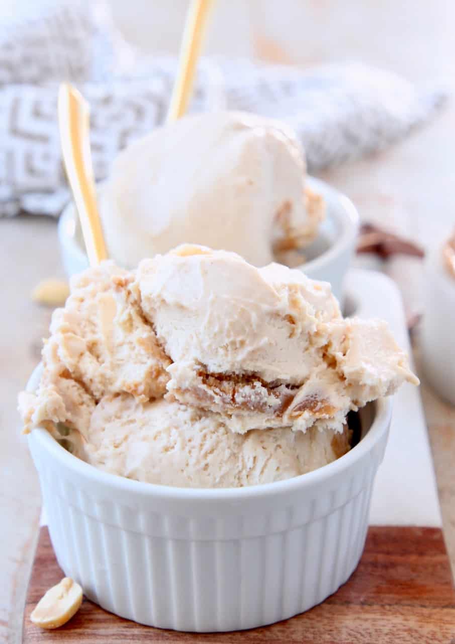 Scoops of peanut butter ice cream in bowls with gold spoons