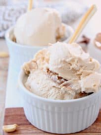 Scoops of peanut butter ice cream in small white bowl with gold spoon