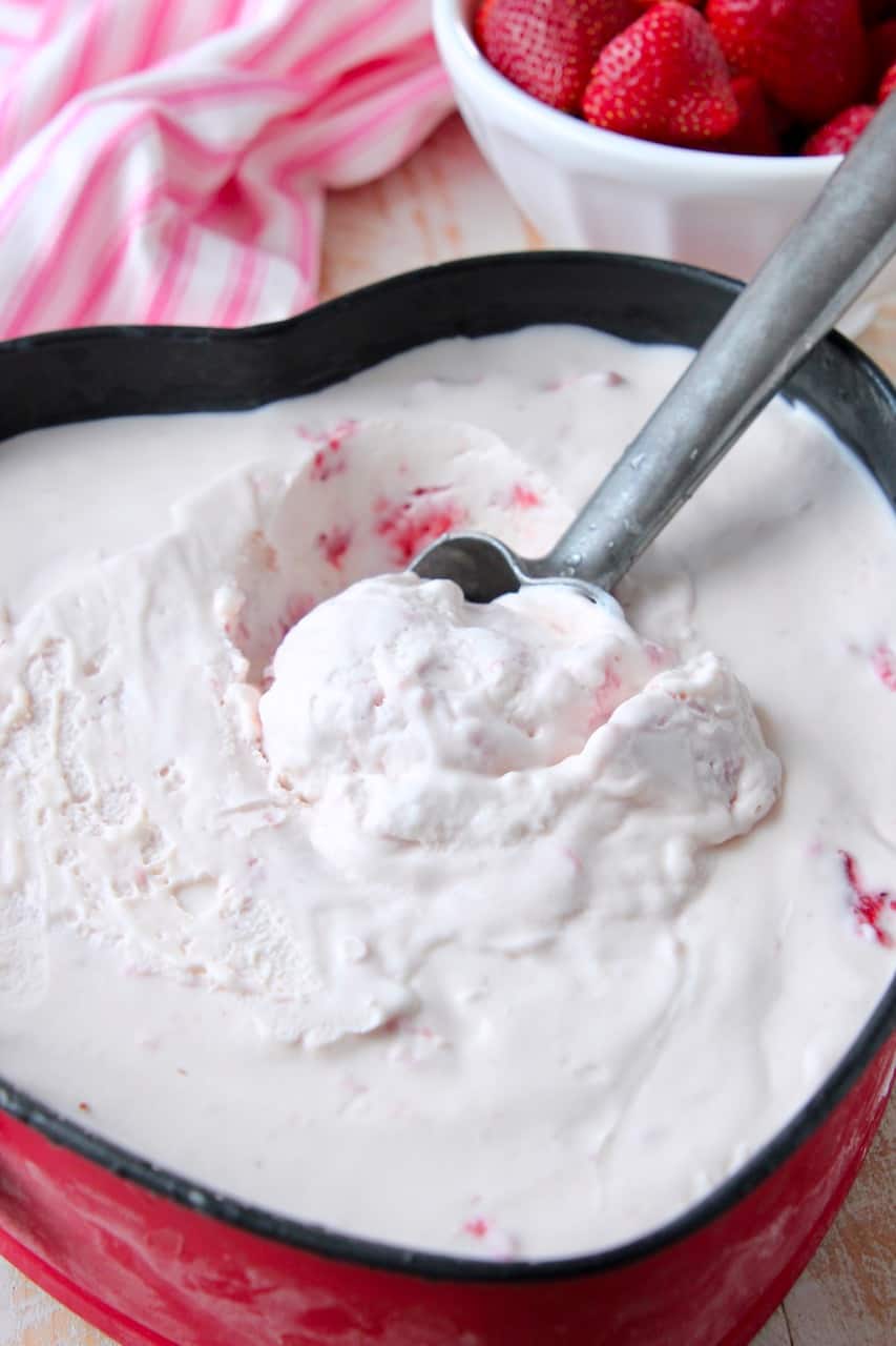 Strawberry ice cream being scooped out of metal pan