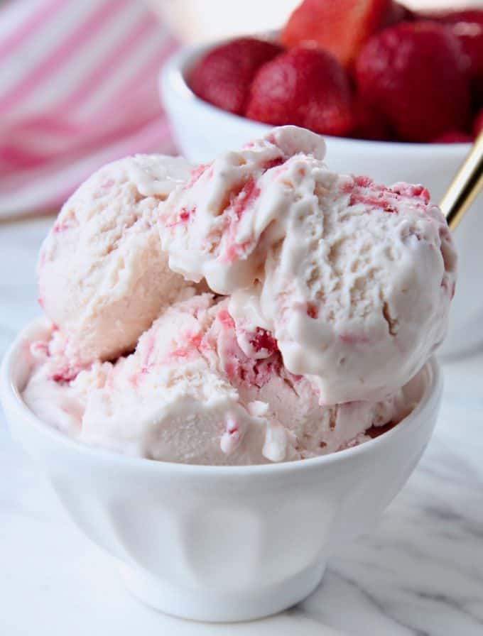 Scoops of strawberry ice cream in white bowl