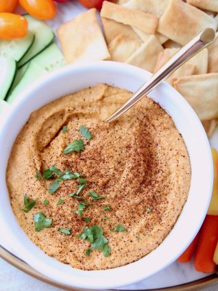 Spicy hummus in bowl topped with chopped cilantro and paprika