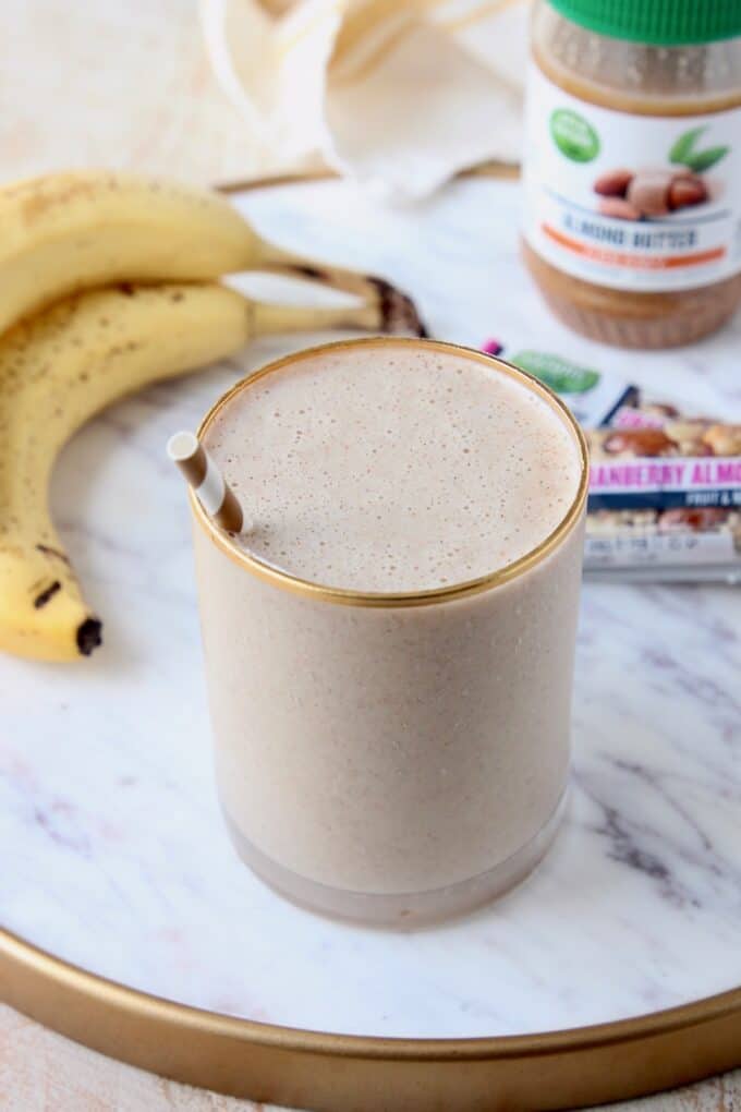 smoothie in glass with straw, sitting next to bananas