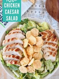 Sliced grilled chicken on caesar salad in bowl