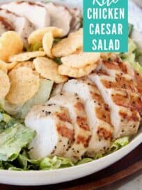Sliced chicken on top of caesar salad