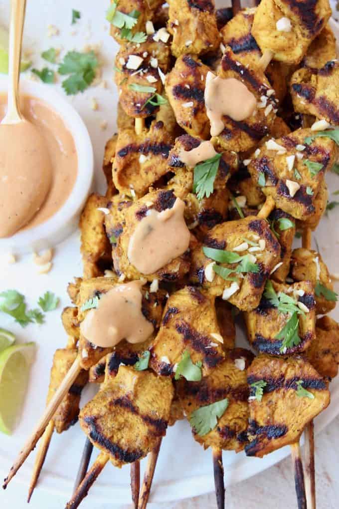 grilled chicken skewers on plate with peanut sauce