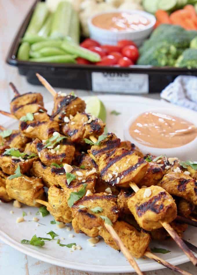 Chicken skewers with peanut sauce and veggie tray on the side