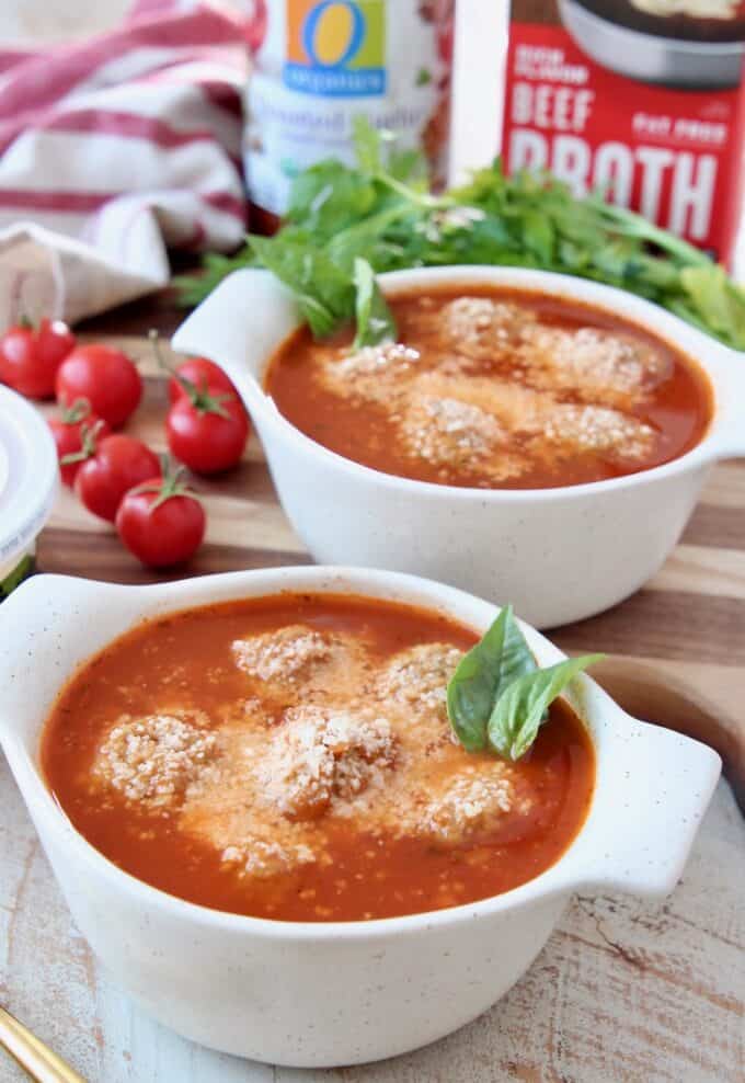 meatball soup in bowls topped with grated parmesan cheese and fresh basil leaves