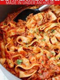 Pasta tossed in meat sauce in large pot with serving spoon in the pot