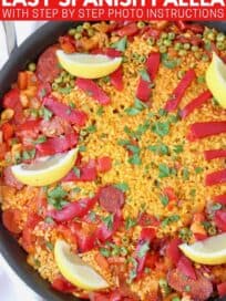 Overhead image of paella in skillet topped with sliced peppers and lemon wedges