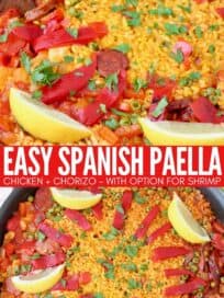 spanish paella in skillet topped with lemon wedges