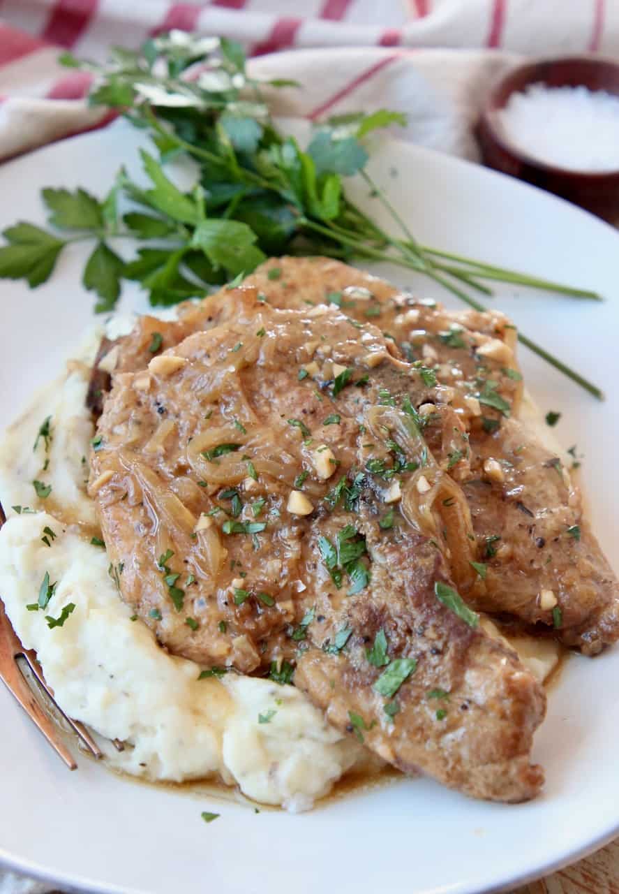pork chops stacked up on plate on top of mashed potatoes