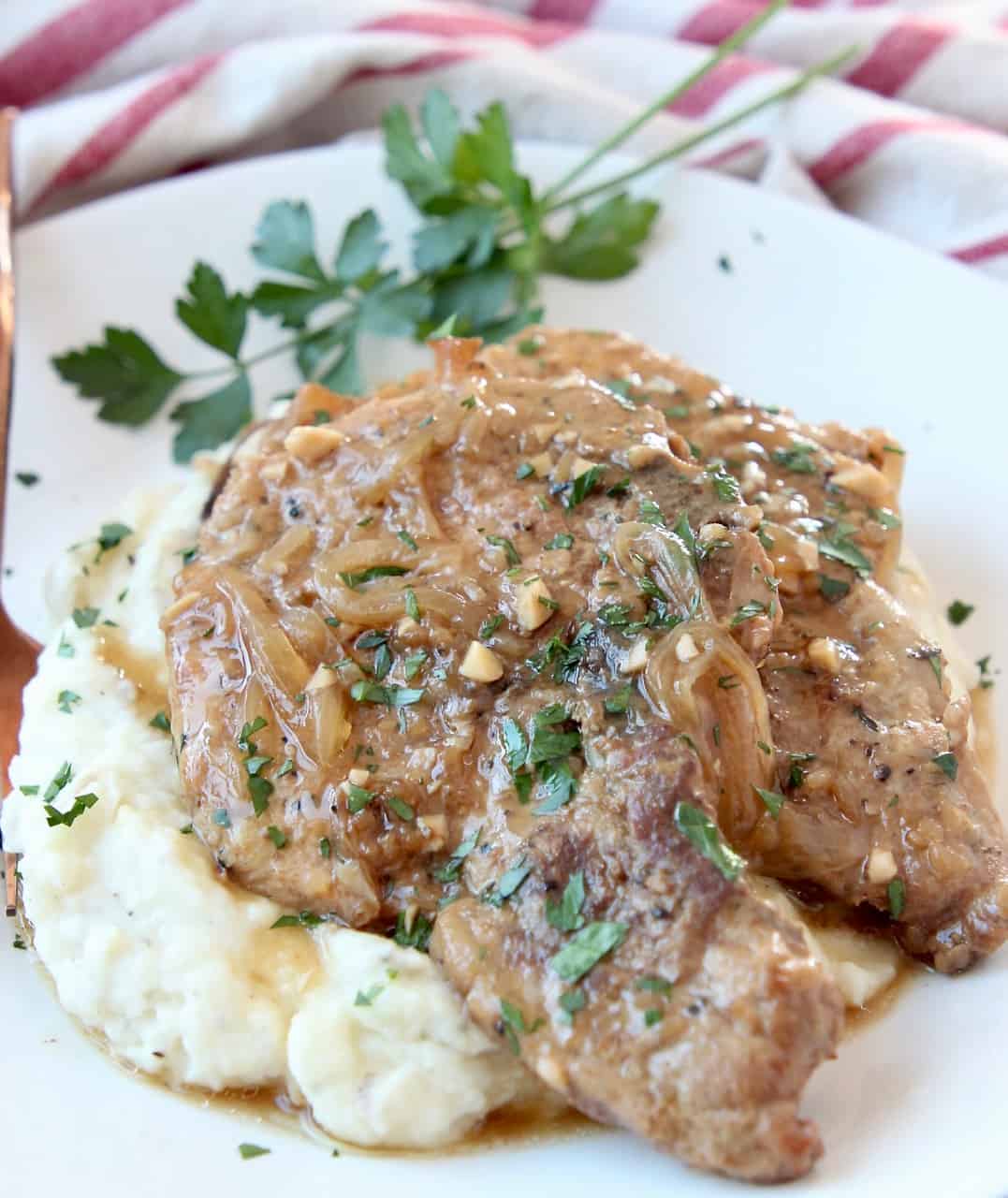 two pork chops stacked on top of each other on plate with mashed potatoes