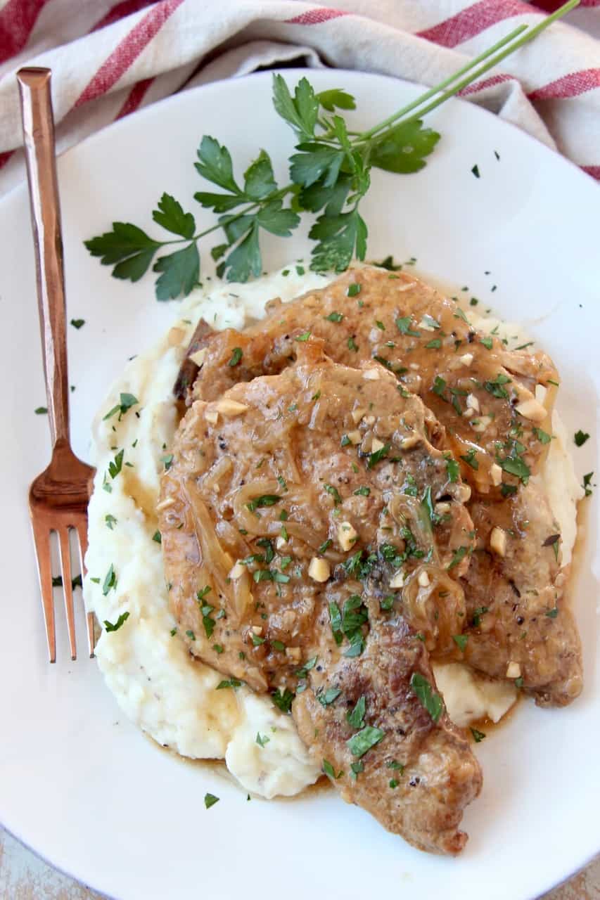 Overhead image of two pork chops on plate with mashed potatoes and brown gravy