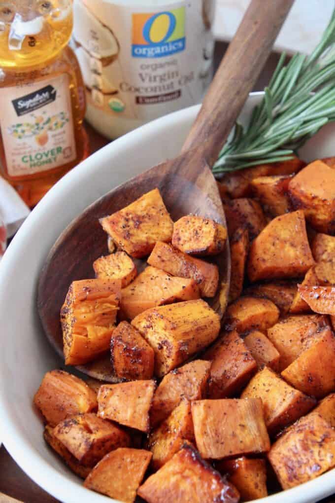 honey roasted cubed sweet potatoes in bowl with wooden serving spoon