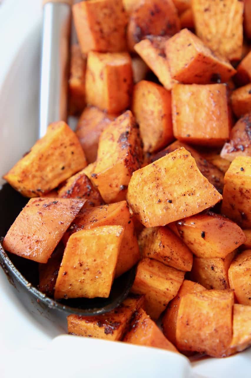 Roasted cubed sweet potatoes in bowl with serving spoon