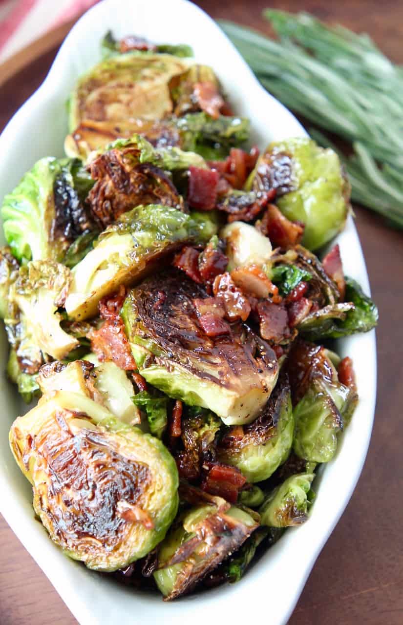 cooked brussels sprouts and bacon in white serving dish